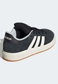 Baskets en daim noir avec un design à trois rayures blanches, semelle en caoutchouc et col rembourré. Présente une languette texturée et un détail de talon avec marque.