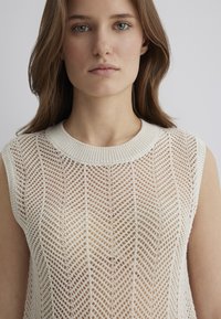 Leichtes Strickoberteil in Creme, mit einem gerippten Rundhalsausschnitt und einem strukturierten, offenen Webmuster im Zickzackdesign.