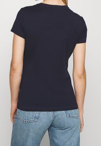 Námořnická modrá krátkosrstá tričko vyrobené z bavlny, s klasickým kulatým výstřihem, hladkým povrchem a úhledným šitím podél okrajů.