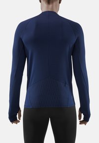 Marineblaue Langarm-Sportshirt mit strukturiertem Rautenmuster, taillierter Passform und einer kleinen Reißverschlusstasche hinten.