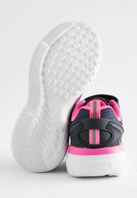 Chaussures de sport noires et roses avec une semelle blanche texturée, des accents roses, une tige en maille et des détails réfléchissants pour plus de visibilité.