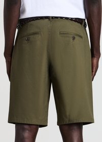 Olive green shorts made of a smooth fabric, featuring two back pockets with buttons and a woven brown belt.