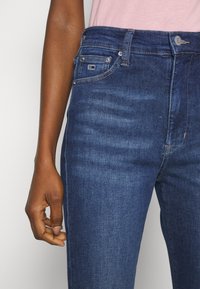Jeans de mezclilla en azul oscuro con un corte clásico, que cuentan con un bolsillo frontal, costuras en contraste y una pequeña etiqueta con logo cerca de la cintura.