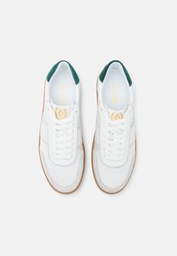 Scarpe da ginnastica bianche con dettagli in suède verde, lacci piatti e suola in gomma. Include dettagli del marchio sulla soletta e strisce laterali.