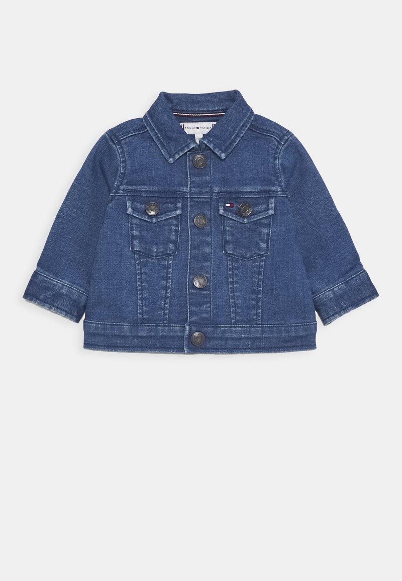 Kurtka dżinsowa w ciemnym niebieskim kolorze z długimi rękawami, zapięciem na guziki, dwoma kieszeniami na piersi i kontrastowymi przeszyciami. Posiada klasyczny kołnierz.