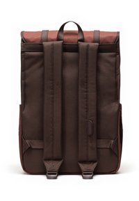 Bruine stoffen rugzak met een oprolbaar ontwerp, uitgerust met twee verstelbare schouderbanden en een handgreep aan de bovenkant. Minimalistische esthetiek.