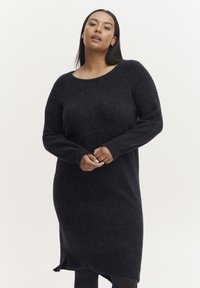 Rochie tricotată din lână întunecată în nuanță de navy, cu mânecă lungă, decolteu rotund, textură cu nervuri și fante laterale pentru libertatea de mișcare. Fabricată dintr-un material moale.