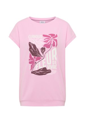 Roze shirt met korte mouwen, met een bloemmotief en witte tekst op de voorkant met de woorden "Curious Fleur de Vivre".