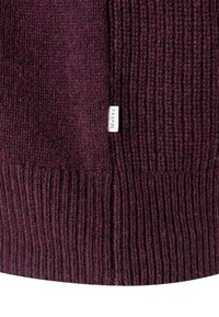 Bordowy sweter z dzianiny o prążkowanej fakturze, z małą metką z napisem "Maerz" z boku. Miękki i gruby materiał.