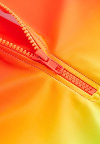 Neon orange zipper partially open on smooth, gradient fabric transitioning from orange to yellow; stitching visible along the edge.