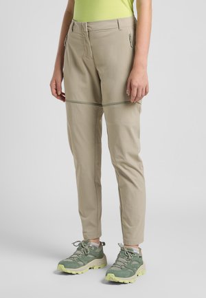 Pantalons d'extérieur beiges, légers, avec une coupe ajustée, dotés de poches zippées et d'un détail de couture horizontal sur les jambes.