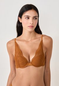 Lace bra in deep amber with a plunging neckline, featuring adjustable straps and a textured pattern. Soft material with seamless edges.