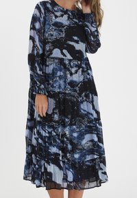 Vestido maxi con un patrón abstracto en azul y negro, que presenta mangas largas, escote redondo y pliegues en capas. Fabricado con tela ligera.