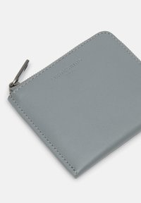 Szary skórzany portfel z zamknięciem na zamek. Gładka tekstura, z dyskretnym przeszyciem i wytłoczonym logo marki z przodu.