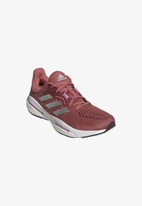 Chaussure de course Adidas marron avec semelle blanche, bandes argentées réfléchissantes, dessus en mesh et semelle intermédiaire amortie pour usage sportif.