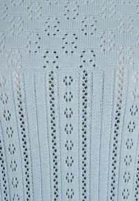 Svetlomodrá pletená látka s vertikálnymi a horizontálnymi vzormi, vrátane radov malých dierok vytvárajúcich kvetinové a geometrické motívy.