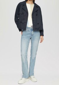 Marineblå cropped jakke med dobbel-knap foran, lys tekstureret top, lyseblå jeans og hvide platform sneakers.