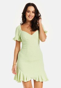Green polka dot dress with short puff sleeves, fitted waist, and ruffled hemline. Smooth fabric and a deep V-neck design.