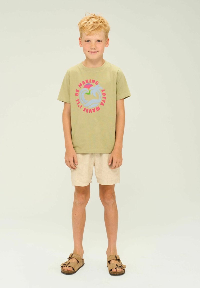 Lichtgroen T-shirt met kleurrijke palmboom graphic; beige linnen shorts; bruine sandalen met twee banden; rechte silhouet, casual stijl.