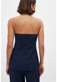 Top sin tirantes de color navy con un cuerpo ajustado, textura suave y cierre de cremallera oculto en la parte posterior. El dobladillo recto termina justo por debajo de la cintura.