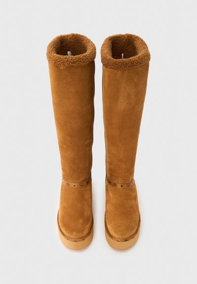 Bottes hautes en daim beige avec une doublure en fourrure douce, une semelle plate marron clair et une bride décorative avec un motif autour de la partie médiane.