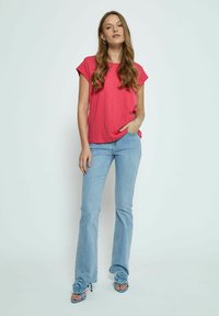 Rosa t-shirt med kort ärm i kombination med ljusblå utsvängda jeans och blå klacksandaler med blommor.