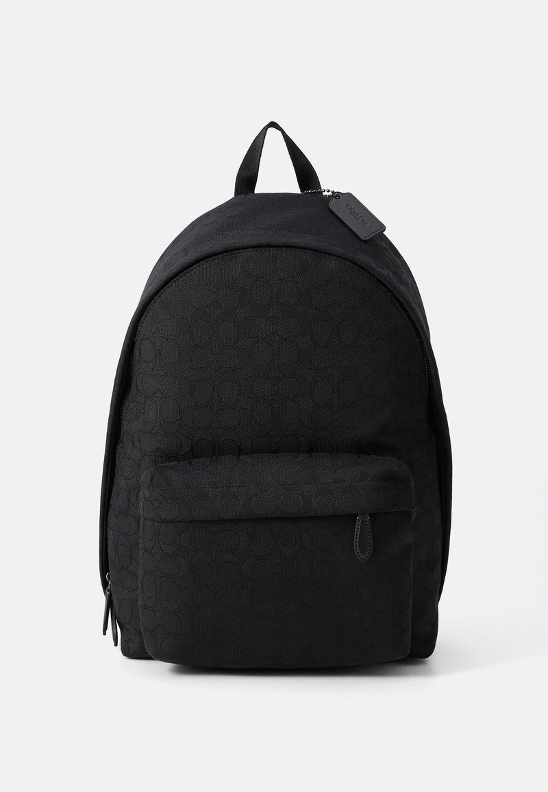 Sac à dos en tissu noir avec un motif circulaire en relief, sommet arrondi, poche zippée à l'avant et une poignée supérieure pour un transport facile.