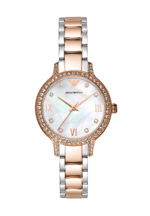 Gold and silver metal watch with a round white mother-of-pearl dial, rose gold accents, and a crystal-studded bezel. Roman numeral markers.