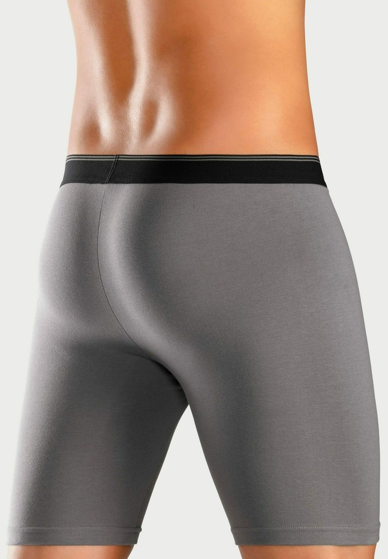 Graue Boxer-Shorts mit glatter Textur, ausgestattet mit einem schwarzen elastischen Bund mit einem kontrastierenden Streifen und einem enganliegenden Design.