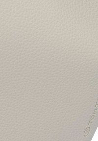 Materiale testurizzato color crema con un motivo a diamante e leggera lucentezza. L'angolo presenta un piccolo dettaglio di branding in rilievo.