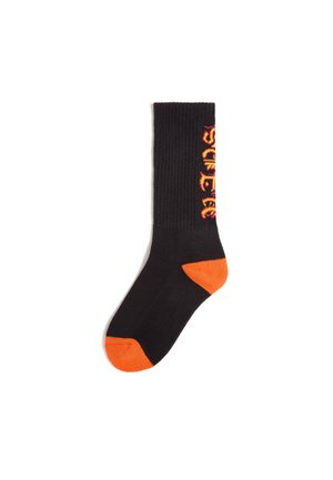 Svart strumpa med orange tå och häl, med vertikal gul och röd flamstil-texter längs sidan.