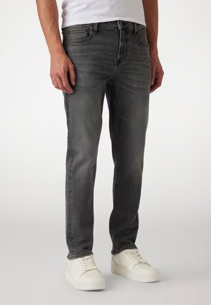 Jeans in denim grigio con una vestibilità slim, dotati di cinque tasche, sfumature leggere e una chiusura classica con bottone, abbinati a sneakers bianche.