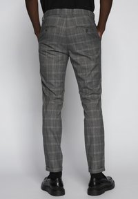 Šedé kostkované kalhoty s úzkým střihem, s zadními kapsami a ohrnovacími lemy. Materiál má hladkou strukturu s jemným vzorem.
