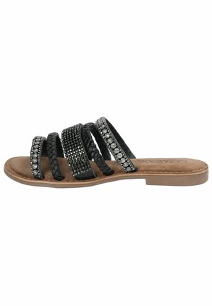 Black slide sandals with multiple textured straps, featuring braided and embellished designs, on a light brown sole.
