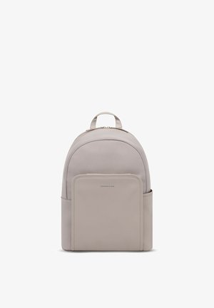 Minimalistischer hellbeiger Rucksack mit abgerundetem Oberteil, Fronttasche, Seitentaschen und oberem Griff, aufrecht stehend vor weißem Hintergrund.