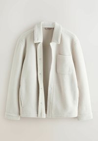 Veste en polaire crème claire avec surface texturée, col chemise et une poche poitrine unique. Comprend des boutons-pression et une doublure intérieure douce.