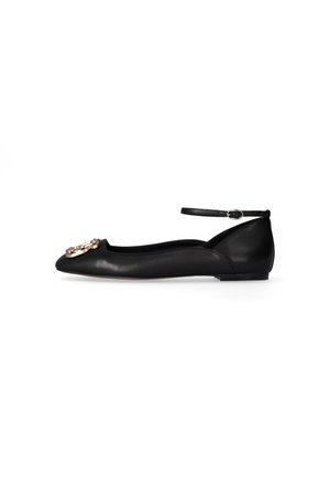 Scarpa piatta in pelle nera con punta affusolata, cinturino alla caviglia con fibbia e decorazione ornamentale dorata sulla punta.