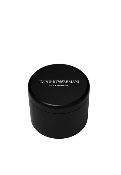 Contenedor circular negro con un acabado mate suave. Muestra "EMPORIO ARMANI SEA EXPLORER" en texto blanco en la tapa.
