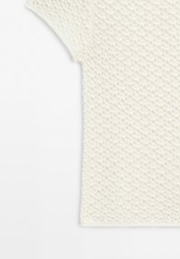 Wit textuurgebreid topje met korte mouwen, een wafeldetail en een ronde halslijn.