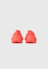 Røde skum sneakers med teksturert overflate, ribbet design på hælen, og utskårne mønstre. Fleksibel og lett konstruksjon.