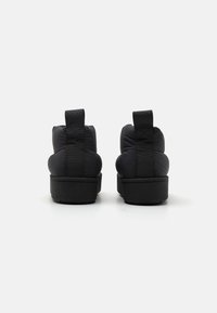 Sorte puffersko med teksturert såle. Har bakre trekkremmer og polstret overdel for komfort. Minimalistisk design.