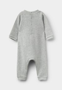 Szary bawełniany kombinezon z długimi rękawami raglanowymi, ściągaczami na mankietach oraz zapięciem na guziki z tyłu. Posiada zaokrąglone nogawki i miękką fakturę.