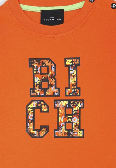 T-shirt in cotone arancione con la scritta in bold nera "RICH" e un motivo grafico colorato all'interno. Collo rotondo con un accento verde.
