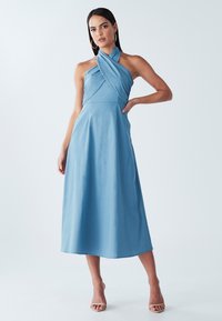 Sinine kaela taha seotud kleit keeruka bodiisomustriga, midi pikkuses, valmistatud siledast kangast ning kujunduselt A-lõikega ja minimaalselt õmblustega.