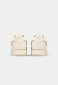 Kremni Nike Air športniki z teksturiranim zaključkom, zaobljenim oblikovanjem in diskretnim logotipom na peti. Gumijast podplat za oprijem.