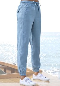 Vaaleansiniset puuvillajoggerit, joissa on joustava vyötärö, nauhaku closure ja joustavat varret. Sivutaskut ja sileä pinta.