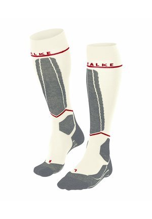 Knielange Socken mit einem cremefarbenen Körper, grauen Akzenten und rotem Branding. Sie weisen strukturierte Muster sowie verstärkte Zehen- und Fersenbereiche auf.
