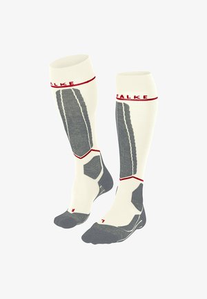 Knielange Socken mit einem cremefarbenen Körper, grauen Akzenten und rotem Branding. Sie weisen strukturierte Muster sowie verstärkte Zehen- und Fersenbereiche auf.