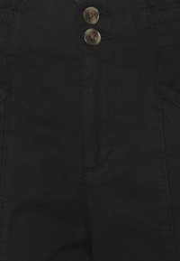 Zwarte denim hoge taille broeken met twee opvallende knopen, zijzakken en subtiele stikdetails aan de voorkant.