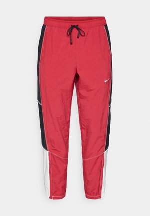 Rode, zwarte en witte Nike trainingsbroek met elastische tailleband en zwarte trekkoorden, met zijpanelen en een klein wit Nike swoosh-logo.